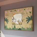 White cow and calf surrounded by pink lotus flowers and green foliage on a beige Pichwai-inspired background