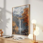 Tall waterfall flowing into a lake beneath snow-capped mountains, surrounded by orange autumn trees and rocky cliffs.